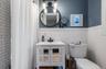 Bathroom featuring a white vanity with integrated sink, black faucet, and mirrored cabinet doors