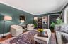 Spacious room featuring wood-finish flooring, deep green painted walls, white crown molding, and built-in shelving units with glass doors