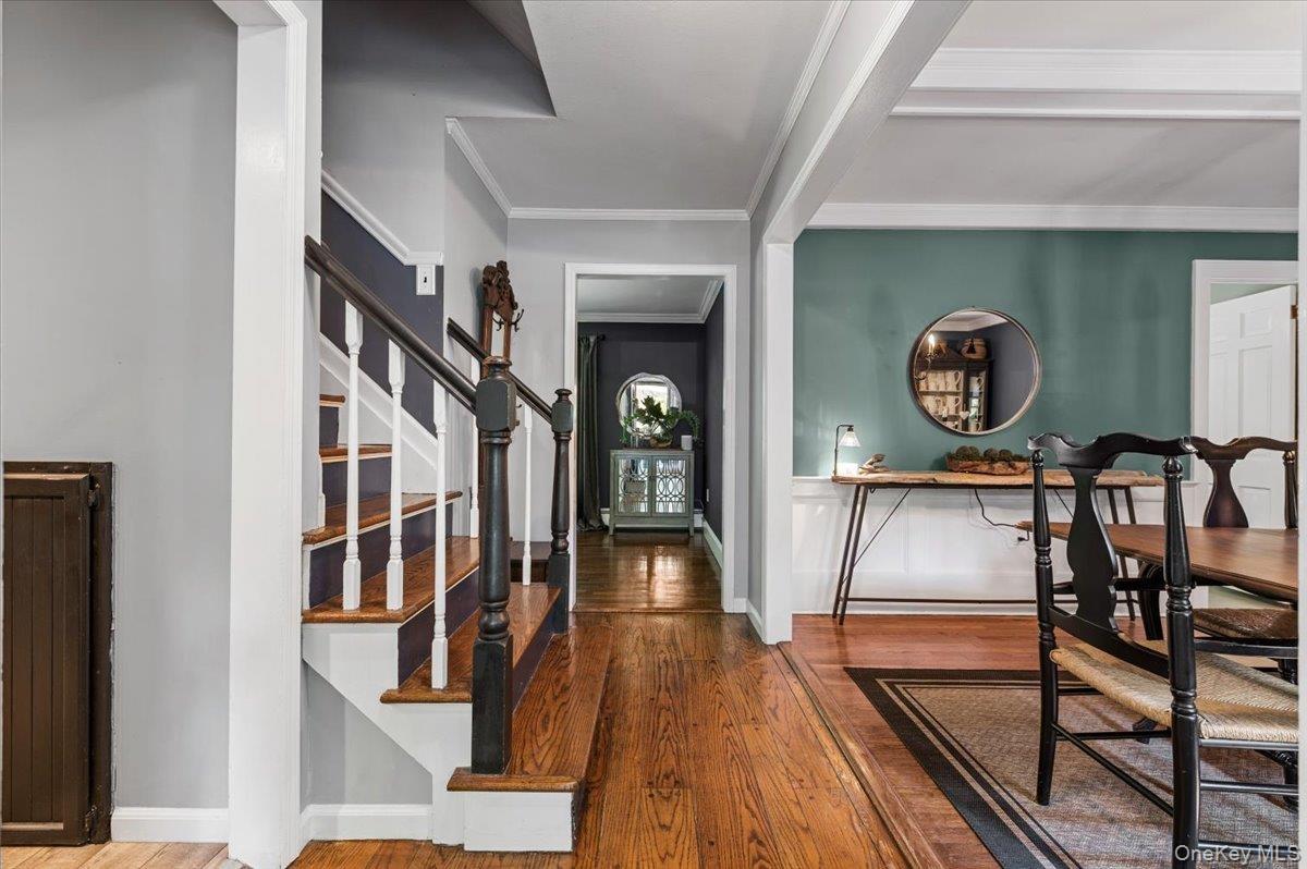 Entry foyer showcasing wood-finish flooring and a staircase with white risers and dark wood treads