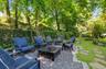 Expansive backyard featuring a stone patio, a manicured lawn, flagstone pathways, and mature trees