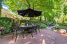 Expansive brick paver patio featuring a dining area under a large umbrella