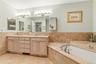 Double sinks, large jacuzzi, so many cabinets, drawers and mirrors.
