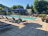 Outdoor pool with tables, umbrellas, chairs lounges.