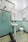Bathroom featuring a glass-enclosed shower, pedestal sink, and patterned floor tiling