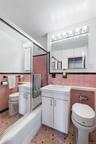 Bathroom featuring a pink and black tiled design, a white vanity with an integrated sink, a mirrored medicine cabinet, a vanity light fixture, and a s