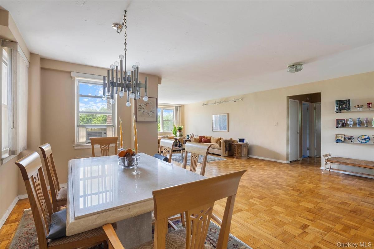 Dining area featuring a contemporary chandelier, large windows with natural light, and parquet wood flooring