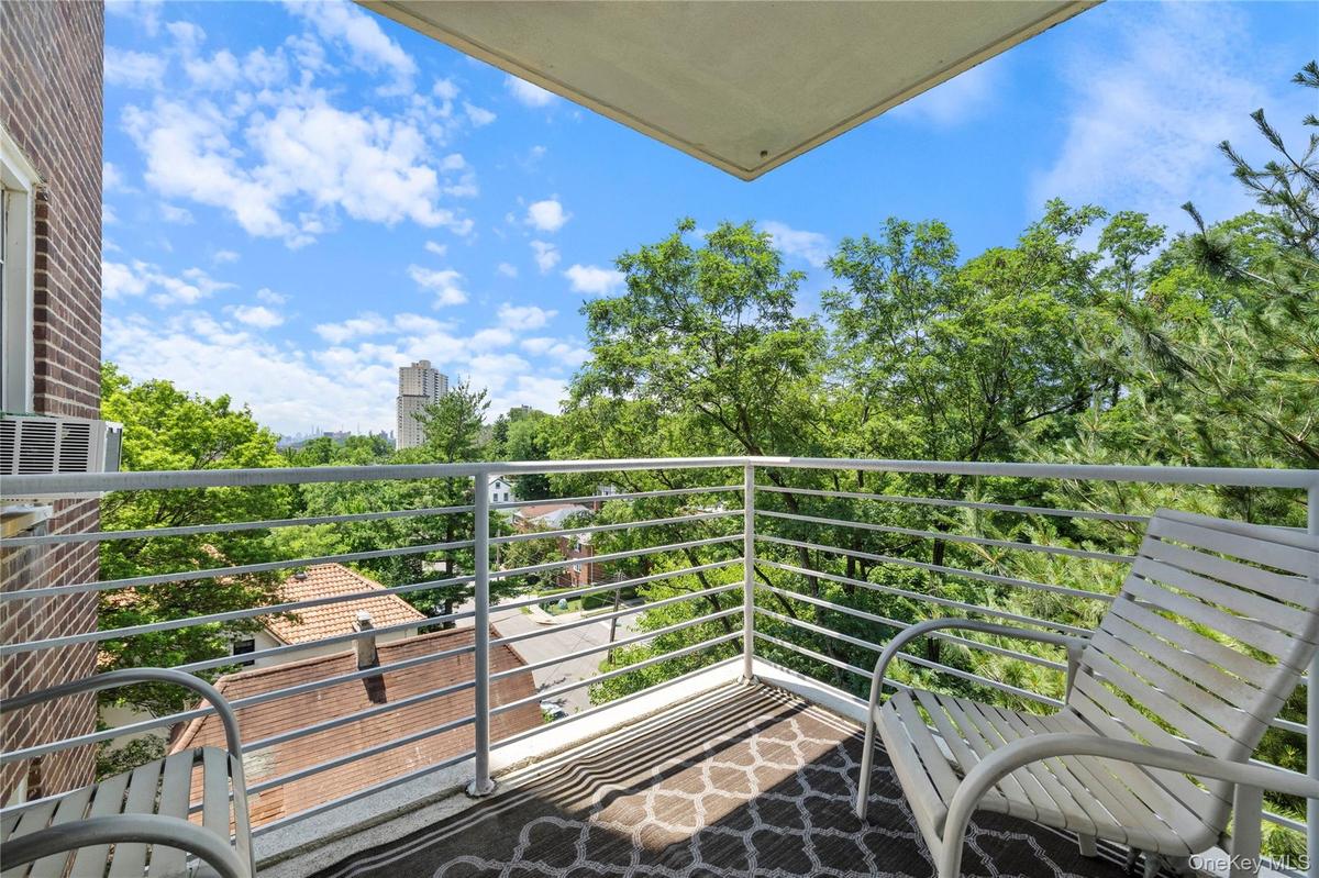 Balcony space featuring a patterned area rug, white metal railing, and a brick exterior wall