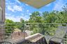 Balcony space featuring a patterned area rug, white metal railing, and a brick exterior wall