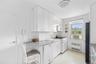 Kitchen featuring white cabinetry with silver hardware, speckled countertops, a white tile backsplash, and linoleum flooring