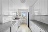 Galley kitchen featuring abundant white cabinetry, a white tile backsplash, and speckled countertops