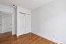 Bedroom featuring wood-finish flooring, white walls, and a built-in closet with sliding doors