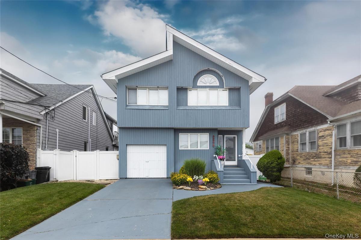 Two-story residence featuring light blue siding, a white garage door, and a light gray concrete driveway