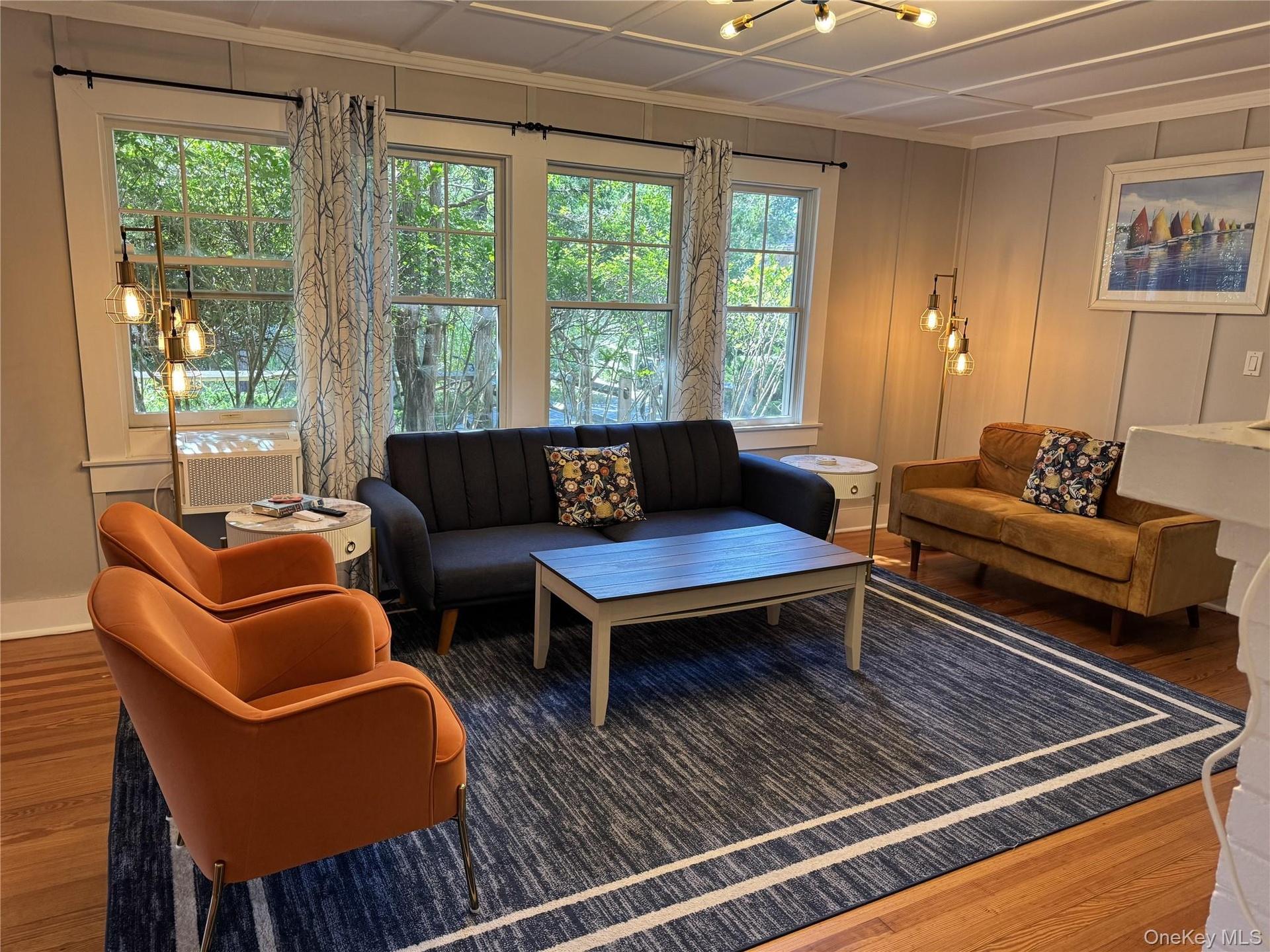 Living room with wood finished floors, healthy amount of natural light, a chandelier, and ornamental molding