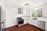 Kitchen featuring appliances with stainless steel finishes, wall chimney range hood, dark wood-style flooring, ornamental molding, and light counterto