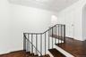 Stairs with arched walkways, wood finished floors, and baseboards