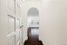 Corridor with arched walkways, dark wood-style flooring, and baseboards