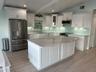 An enjoyable beachfront kitchen with sleek countertops and large windows offering a stunning ocean view.