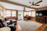 Spacious living area featuring wood-finish flooring, a ceiling fan with integrated lighting, and multiple windows