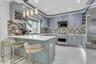 Custom cabinetry with integrated wine rack, stainless steel top of the line appliances, white quartz countertops, over-sized porcelain tile flooring, 