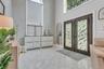 Double iron entry doors featuring crushed glass panels, stacked stone accent wall, over-sized elliptical windows providing a warm ambiance of light, e