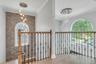 2nd story entry view, Stacked stone accent wall,Custom wood and decorative iron railing, glass chandelier, front pictureseque elliptical window adding