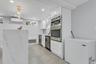 Bonus: Contemporary kitchen space featuring a waterfall island with veined quartz, recessed lighting, and a gold-tone linear chandelier