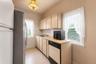 Kitchen featuring tile flooring, a stainless steel refrigerator, neutral cabinetry, a built-in dishwasher, and a window with natural light