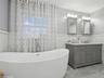Bathroom featuring a tub, vanity, and tile walls