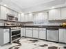 Kitchen with decorative backsplash, white cabinetry, sink, and stainless steel appliances