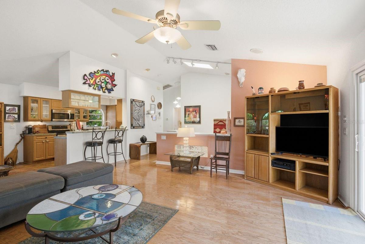 Living Room to kitchen and stairs with vaulted ceilings and skylight.