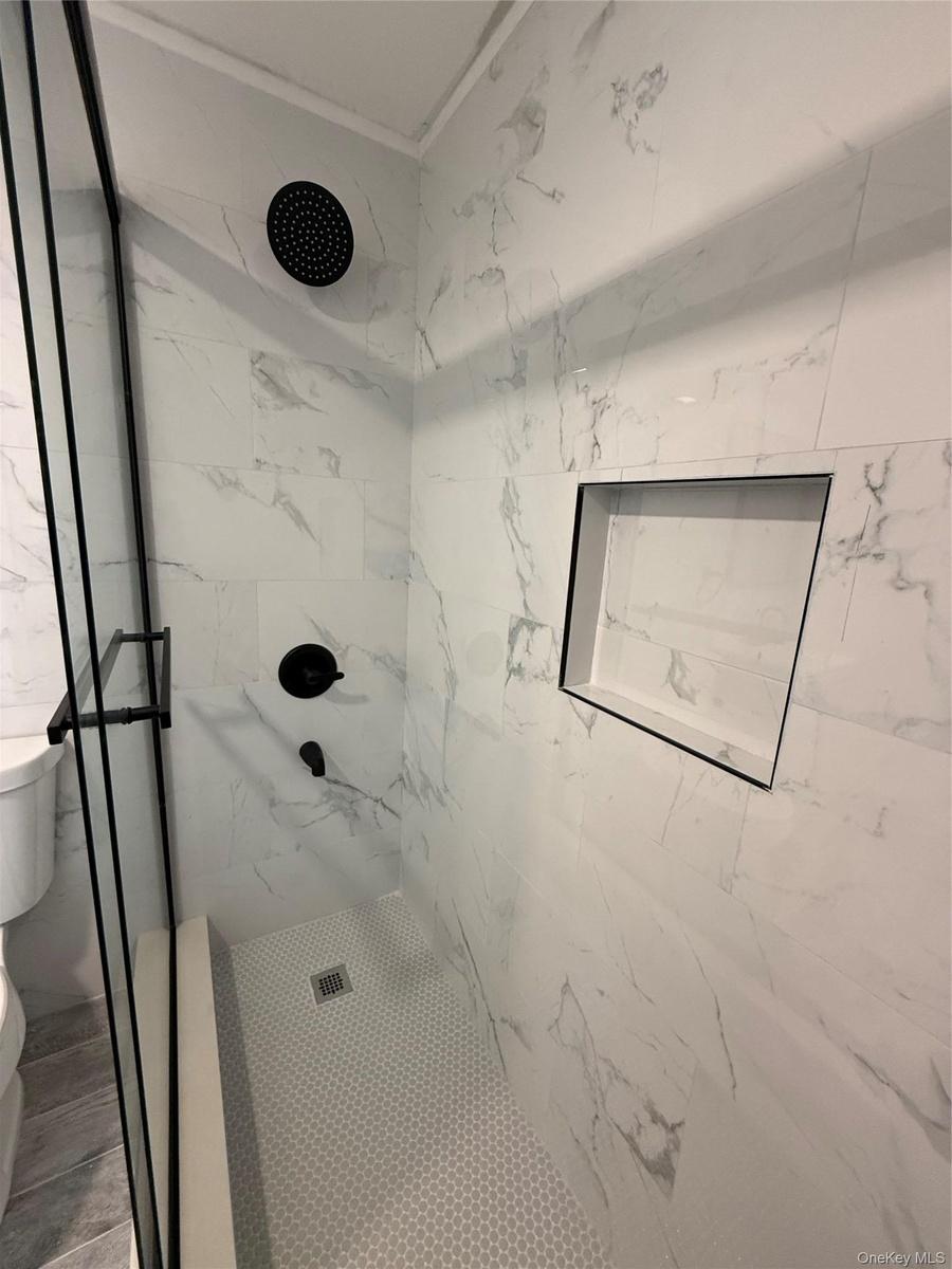 Bathroom featuring a marble finish shower and ornamental molding
