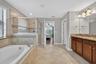 Primary En-Suite Bathroom with Dual Vanities, Granite Countertops, Garden Soaking Tub with Window, Shower Stall with Glass Frame, Private Water Closet