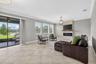 View of Double Sliding Glass Doors and Living Room with Crown Molding, 3 Stunning Windows, Accent Wall with Stone Accent and Chandelier.
