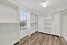 Primary Expansive Walk-In Closet with LVP Flooring, Window for Natural Light, Custom Cabinets, Drawers, Shelving and Storage.