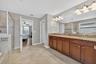 Primary En-Suite Bathroom with Dual Vanities, Granite Countertops, Garden Soaking Tub, Shower Stall with Glass Frame, Private Water Closet, Linen Clos