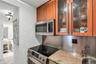 Kitchen area featuring stainless steel Bosche and Perlick under the Cabinet, Refrigerator appliances, wood-finish cabinetry with decorative glass inse