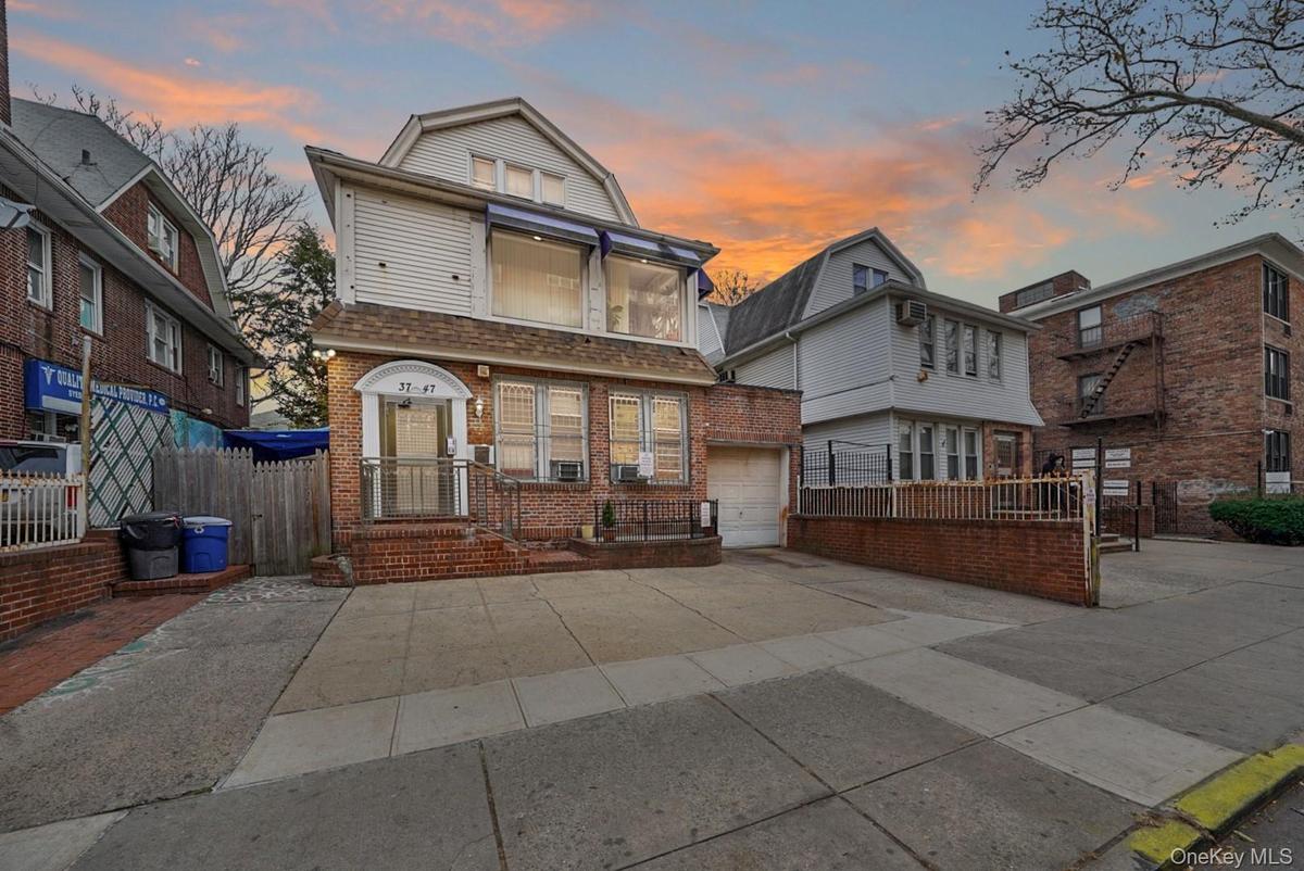 Front exterior elevation of 37-47 76th Street, Jackson Heights, NY 11372, featuring a three-family residence with a private driveway, attached garage,