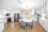 Dining room with stacked washer / dryer, light wood-style floors, ornamental molding, and a chandelier