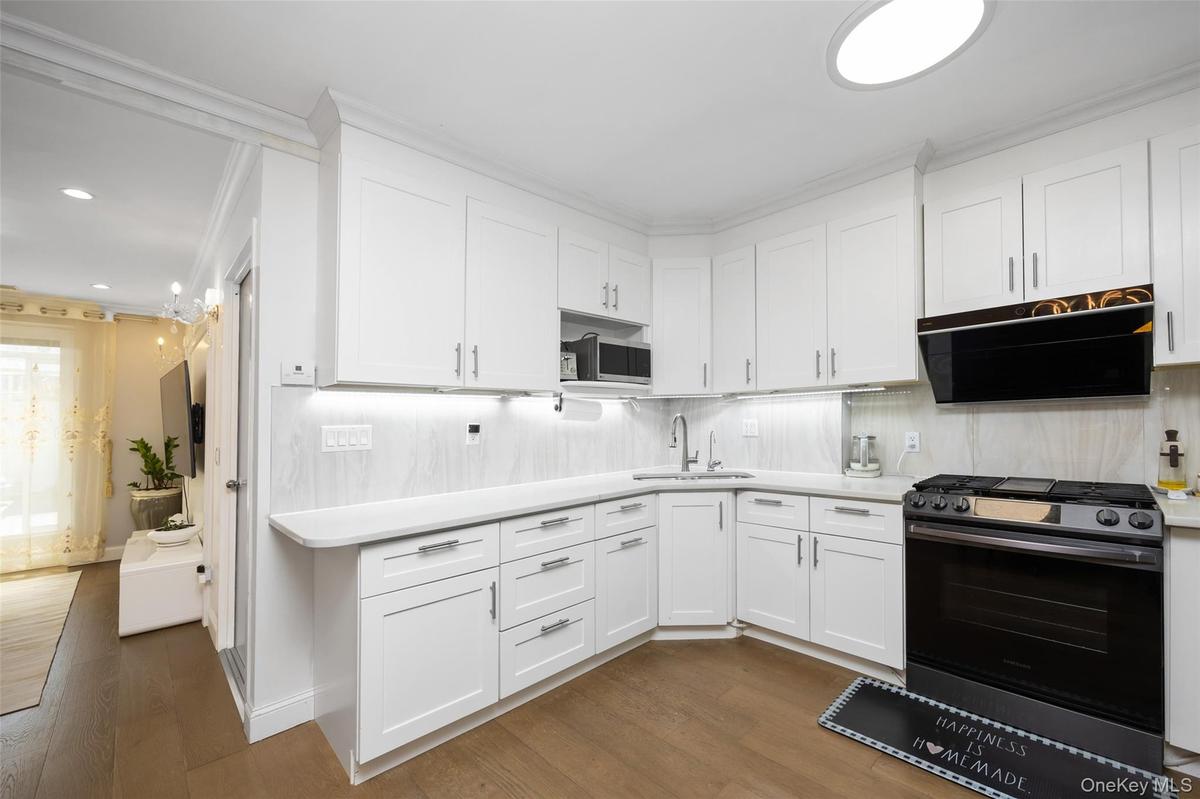 Kitchen featuring stainless steel appliances, white cabinetry, dark wood-style floors, exhaust hood, and tasteful backsplash