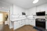 Kitchen featuring stainless steel appliances, white cabinetry, dark wood-style floors, exhaust hood, and tasteful backsplash