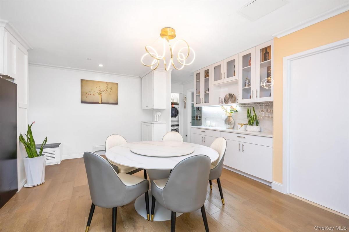 Dining room with stacked washer and clothes dryer, light wood-style floors, a chandelier, crown molding, and recessed lighting