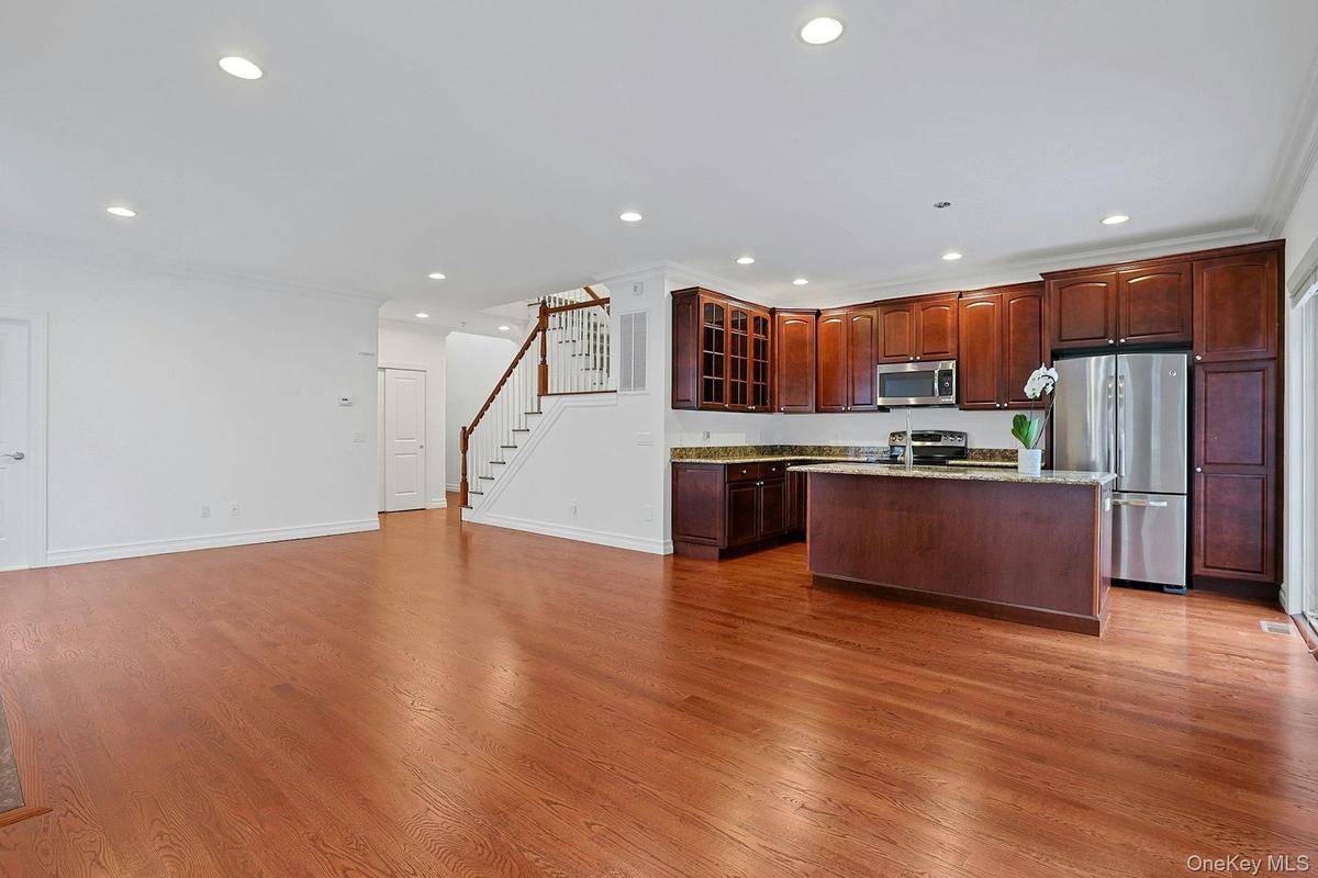 Well-appointed with rich wood cabinetry, granite countertops, stainless steel appliances, and a center island with seating.