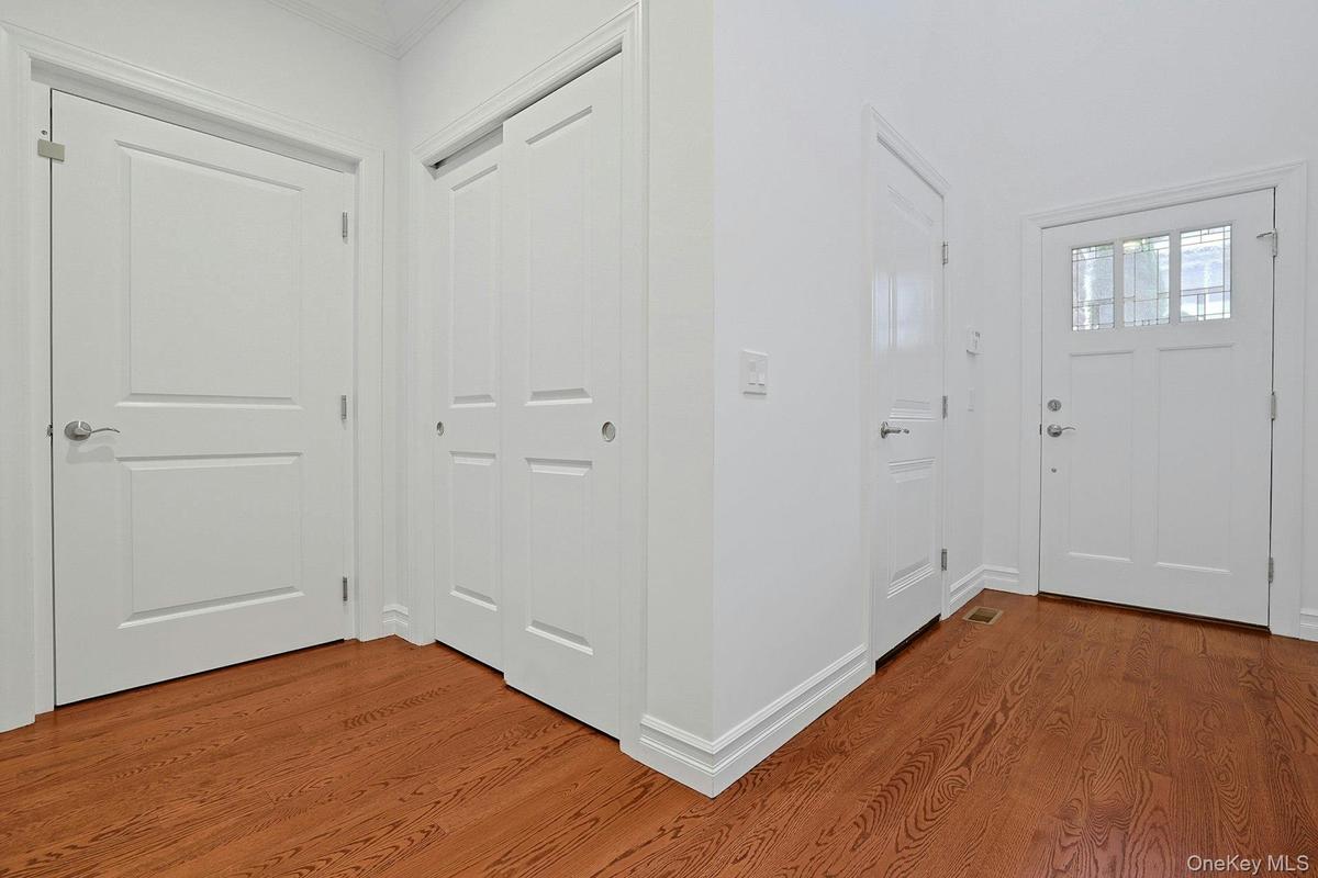 A welcoming entry with hardwood floors, generous coat closet space, powder room, and two-car garage access.