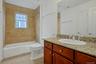 The beautifully appointed hall bath features a granite-topped vanity, warm stone tile, and a full tub/shower combination, blending style and functiona