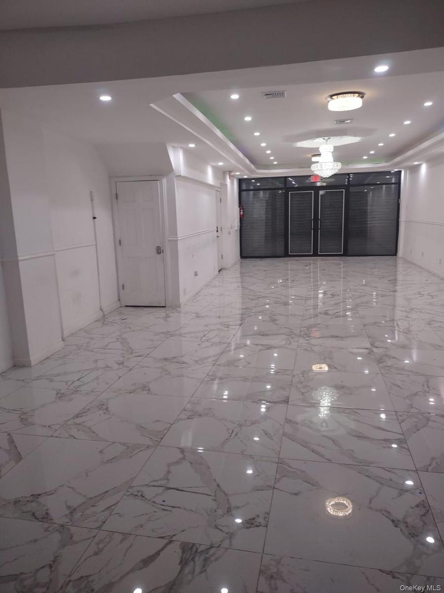 Corridor with light marble finish floors, recessed lighting, and a raised ceiling