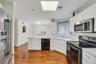 Kitchen featuring wood-finish flooring, white cabinetry, and a suite of stainless steel and black appliances, including a built-in microwave, range, a