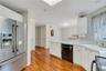 Kitchen featuring wood-finish flooring, white cabinetry, integrated stainless steel refrigerator, and built-in dishwasher