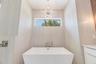 The luxurious primary suite offers a spa-inspired retreat featuring a freestanding soaking tub, oversized walk-in shower with rain head and handheld s