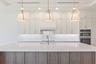 The gourmet kitchen is a true showpiece, featuring full-height custom cabinetry, an oversized 11-foot quartz island with storage on both sides, marble
