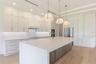 The gourmet kitchen is a true showpiece, featuring full-height custom cabinetry, an oversized 11-foot quartz island with storage on both sides, marble